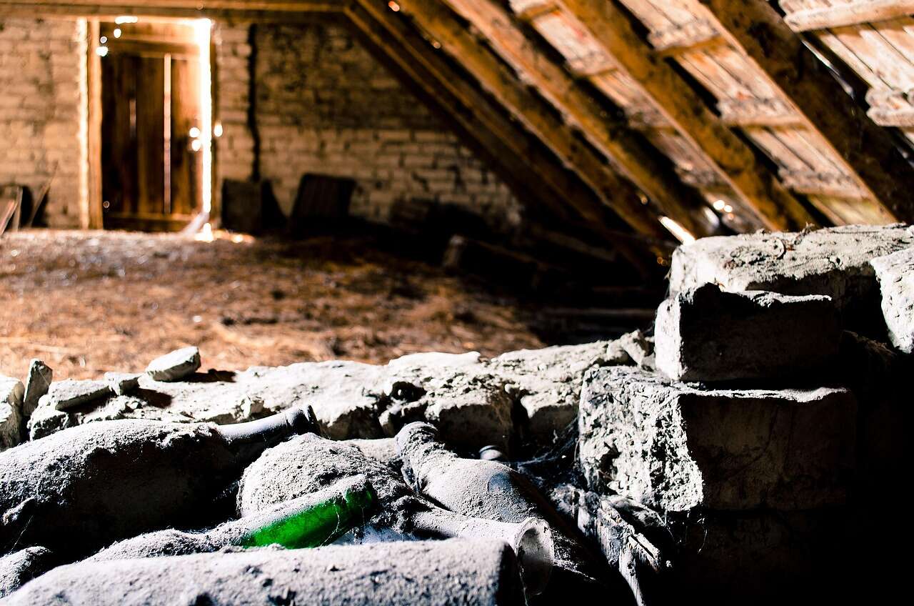 Old disturbed insulation and debris on the floor of a dim attic