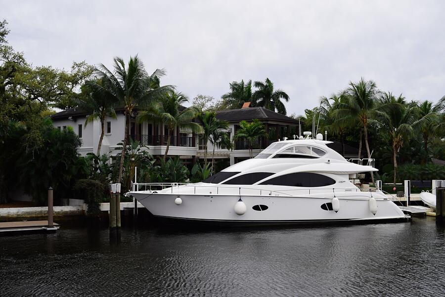 Palms and hedge along a canal sea wall with a yacht moored beside them