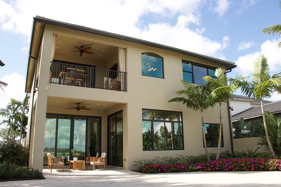 A two-story stucco house with a barrel tile roof and queen palms